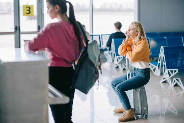 Annoiato Giovane Donna Seduta Sulla Valigia Nel Terminal Dell Aeroporto — Foto Stock