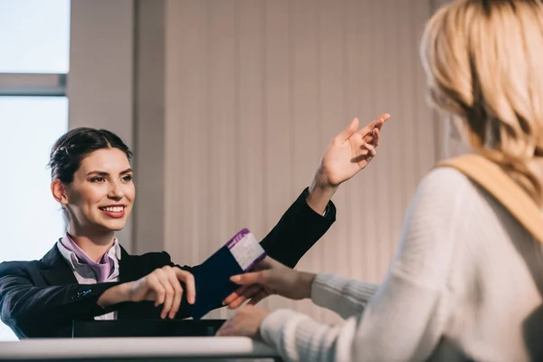 Leende Flygplats Arbetare Visar Vägen Till Unga Resenären Vid Incheckningsdisken — Stockfoto