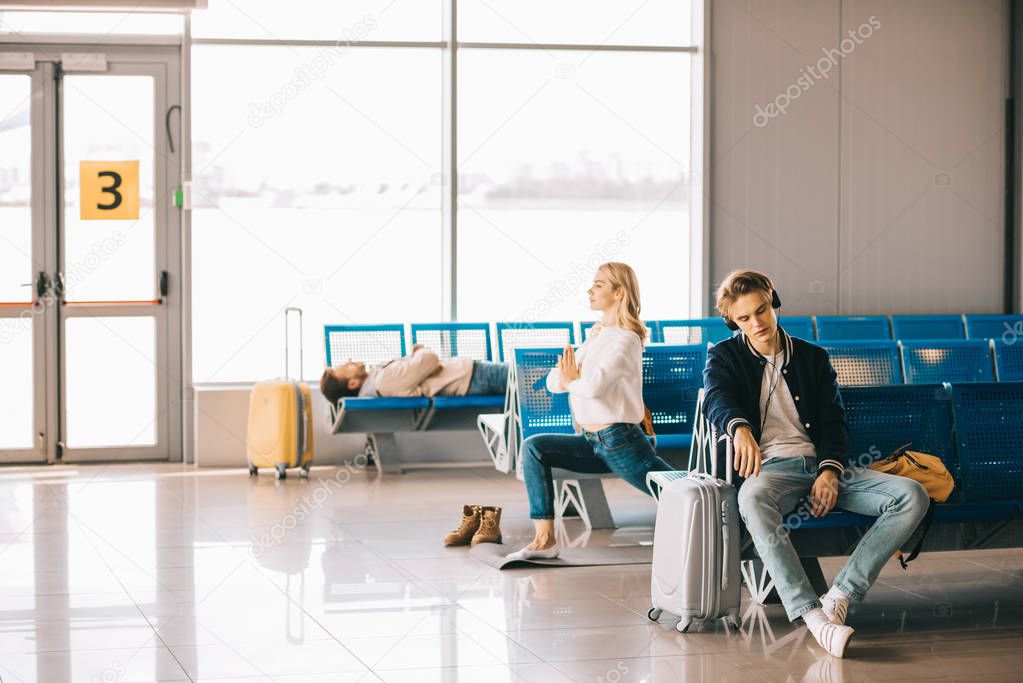 young woman practicing yoga while waiting for flight in airport terminal 