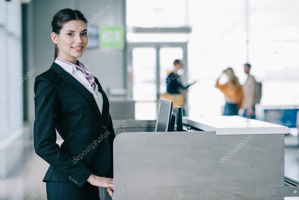 beautiful young woman smiling at camera while working at check-in desk in airport 