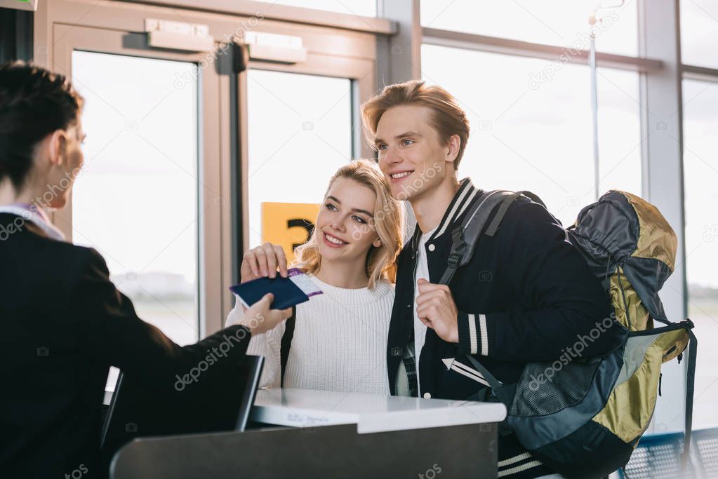 happy young couple at check-in desk in airport 