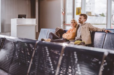 seçici odak birlikte oturan ve uçuş havaalanında bekleyen genç çift 