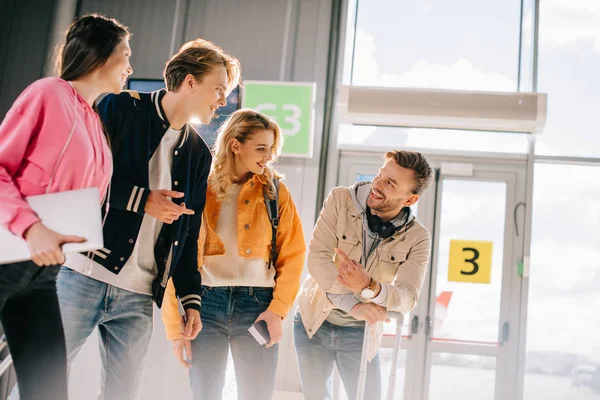 Jovens Amigos Felizes Sorrindo Uns Aos Outros Enquanto Esperam Terminal — Fotografia de Stock Grátis