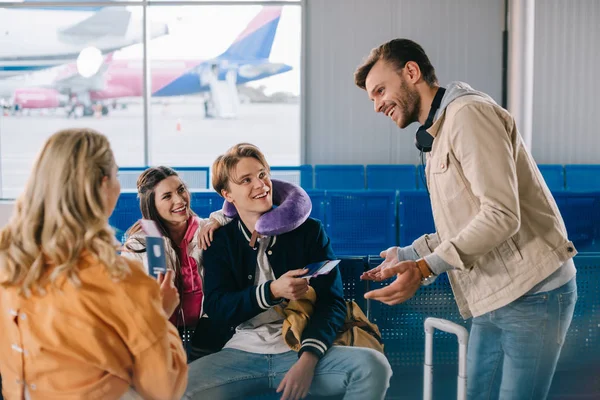 Jóvenes Sonrientes Revisando Documentos Mientras Esperan Vuelo Terminal Del Aeropuerto — Foto de stock gratis