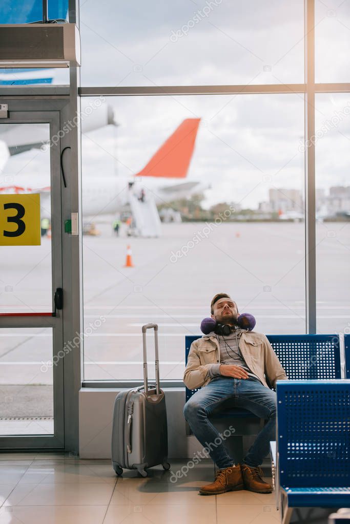 young man sleeping while waiting for flight in airport