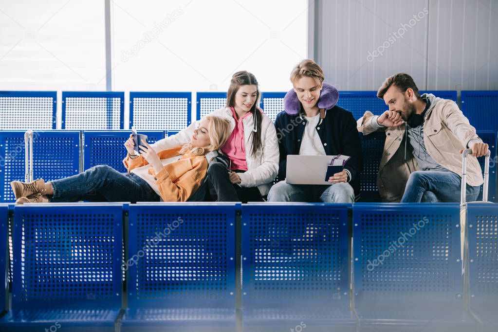 friends using laptop while waiting for flight in airport terminal