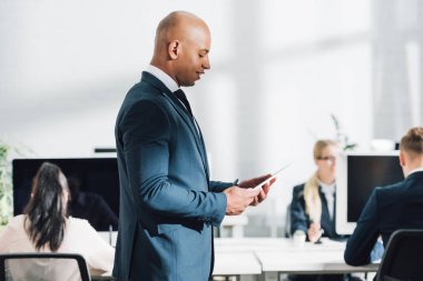 gülümseyen genç Afro-Amerikalı işadamı dijital tablet kullanma açık alan office yan görünüm