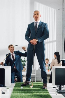 kendine güvenen genç Afro-Amerikalı işadamı meslektaşım Office ile golf oynarken kameraya bakıyor