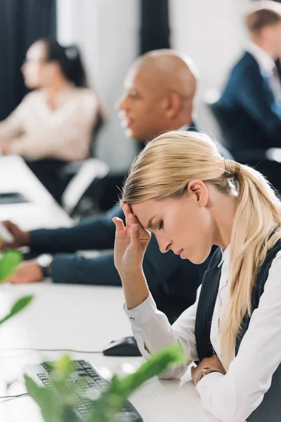 職場で座っている頭痛と動揺の若い実業家の側面図  — 無料ストックフォト