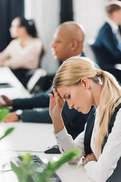 Side view of upset young businesswoman with headache sitting at workplace — Stock Image Side View Upset Young Businesswoman Headache Sitting Workplace Royalty Free Stock Images