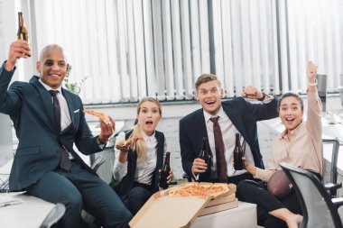 bira içip pizza ofiste yemek yaparken kameraya bakarak heyecanlı genç arkadaşları