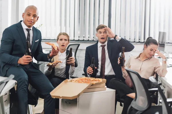 Шокированные Молодые Бизнесмены Пьют Пиво Едят Пиццу Офисе — стоковое фото