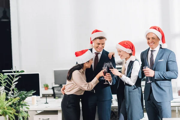 快乐的年轻同事在圣诞老人帽子喝酒 庆祝圣诞节在工作场所 — 图库照片