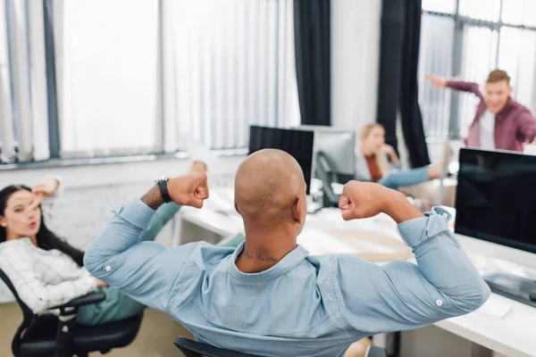 Baksidan Afroamerikanska Mannen Visar Biceps Och Unga Kollegor Roligt Office — Stockfoto