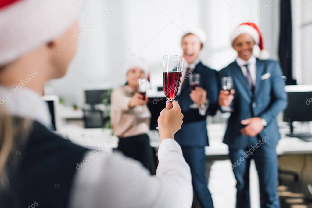 selective focus of young coworkers drinking wine and celebrating new year in office