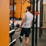 Athletic young sportsman with artificial leg standing near gymnastics ladder at gym