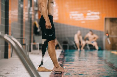 yapay bacak ayakta havuz kenarı kapalı yüzme havuzu ve kontrol su sıcaklığı ile kaslı sporcu kadeh kırpılmış