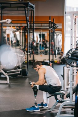 spor salonunda oturan yapay bacak ile yorgun genç sporcu