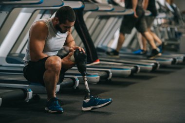yapay bacak spor salonunda koşu bandı üzerinde oturan genç sporcu bitkin