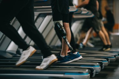 diğer insanlarla spor salonunda koşu bandı üzerinde çalışan yapay bacak ile sporcu kadeh kırpılmış