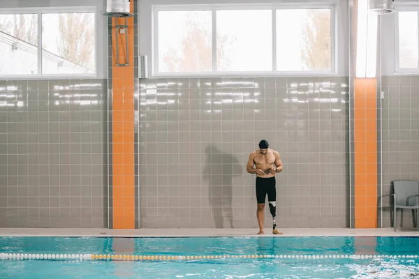 英俊的年轻运动员与人造腿站在池畔在室内游泳池 — 图库照片