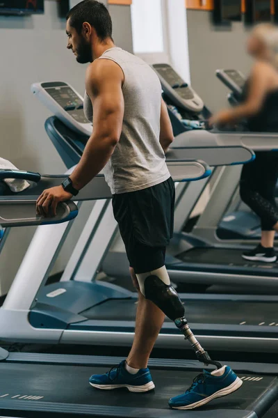 義足のジムで Treadmilsl の上を歩くとハンサムな若いスポーツマン — ストック写真