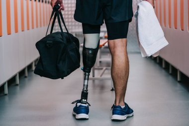 sporcu yapay bacak ayakta havlu ve çanta ile spor salonu soyunma odasında ile kadeh kırpılmış