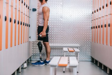 spor salonu dolabına şeyler alarak yapay bacak ile sporcu kadeh kırpılmış