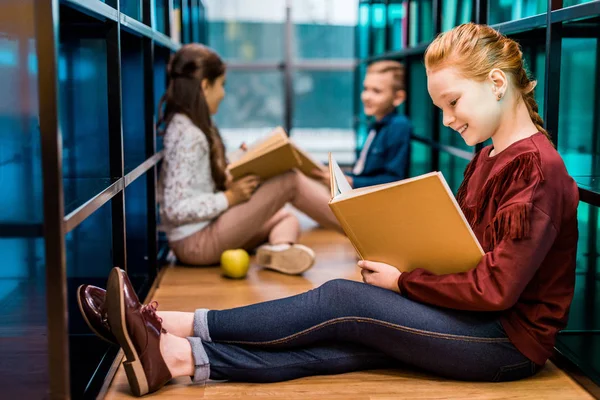 Urocza Uczniów Siedząc Podłodze Czytanie Książek Bibliotece — Zdjęcie stockowe