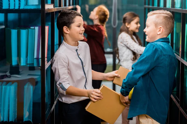 Kitaplar Holding Diğer Her Kitaplıkta Gülümseyen Güzel Mutlu Schoolkids Yan — Stok fotoğraf