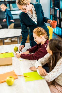 Kitaplığı'nda eğitim okul bakarak gözlük gülümseyen genç öğretmen  
