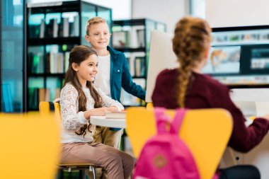 sevimli gülümseyen schoolkids Kitaplığı'nda masaüstü bilgisayarlar ile eğitim