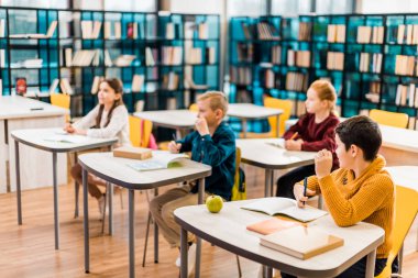 masaları oturma ve uzakta ders sırasında kitaplığında arayan çocuk 