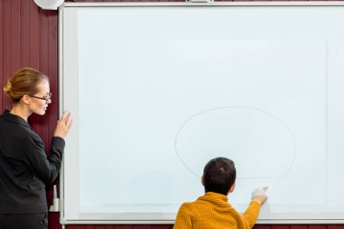 Genç öğretmen öğrenci interaktif beyaz tahta ile eğitim bakarak