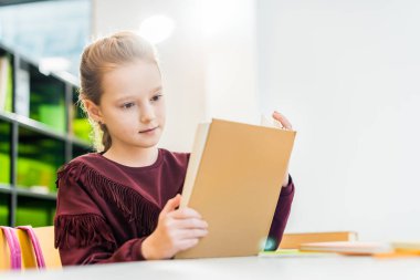 güzel kız öğrenci Kitaplığı'nda otururken kitap okuma