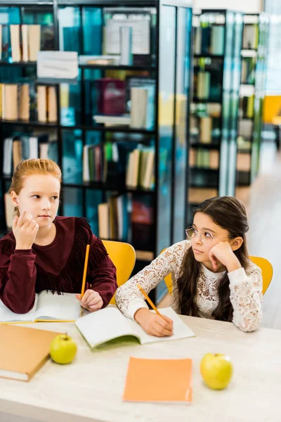 Schoolmeisjes Schrijven Met Potloden Terwijl Het Bestuderen Bibliotheek — Stockfoto