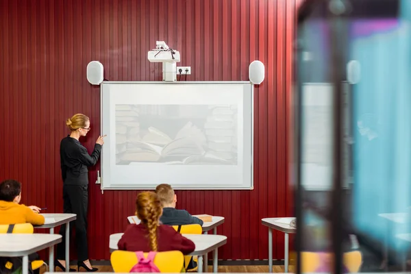 librarian making presentation at interactive whiteboard to schoolchildren