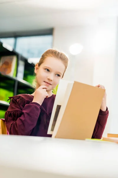 Vackra Skolflicka Sitter Vid Skrivbord Och Läsebok Biblioteket — Stockfoto