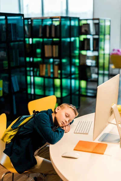 ライブラリ内のコンピューターを机の上眠っているバックパックと少年のハイアングル — ストック写真