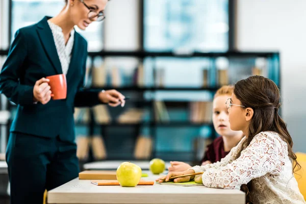 Young Teacher Holding Cup Looking Schoolkids Studying Library Stock Image