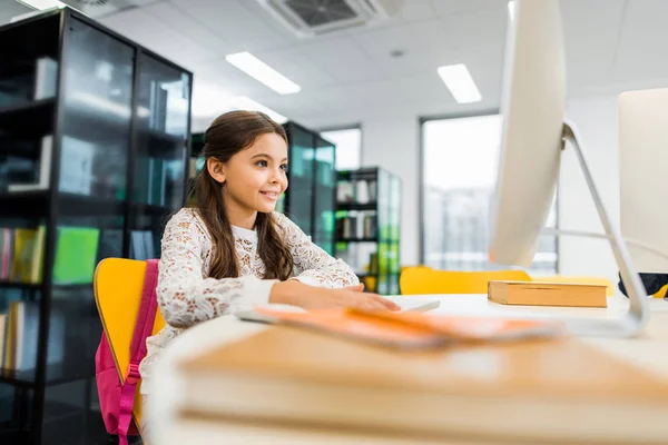 Entzückend Lächelnde Schulkind Mit Desktop Computer Der Bibliothek Stockfoto