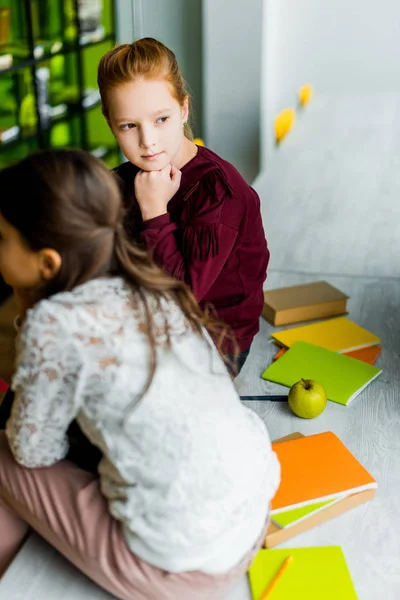 Adorabili Studentesse Sedute Sulla Scrivania Con Libri Distogliendo Sguardo Biblioteca Foto Stock