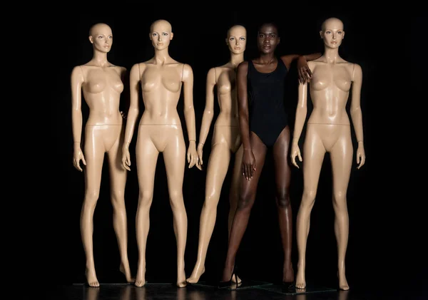 Vue pleine longueur de belle jeune femme afro-américaine en maillot de bain debout entre mannequins et regardant la caméra sur noir — Photo de stock