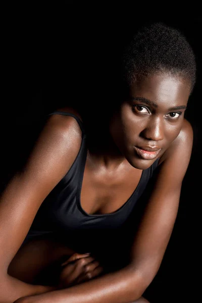 Porträt einer schönen jungen afrikanisch-amerikanischen Frau, die isoliert auf schwarz in die Kamera blickt — Stockfoto