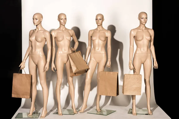 Naked bald mannequins with shopping bags on white — Stock Photo