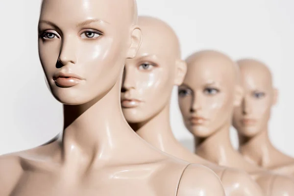 Close-up view of naked bald mannequins in row on white, selective focus — Stock Photo