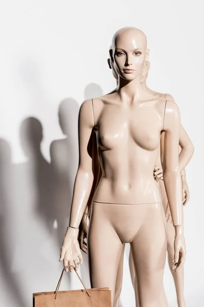 Maniquí calvo desnudo con bolsa de compras y sombra en blanco - foto de stock