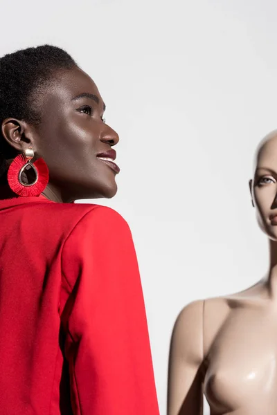 Vue à angle bas de belle femme afro-américaine souriante debout près de mannequin et regardant loin sur blanc — Photo de stock