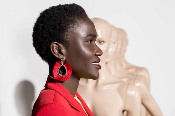 Vue latérale de belle afro-américaine souriante regardant loin et mannequins sur blanc — Photo de stock