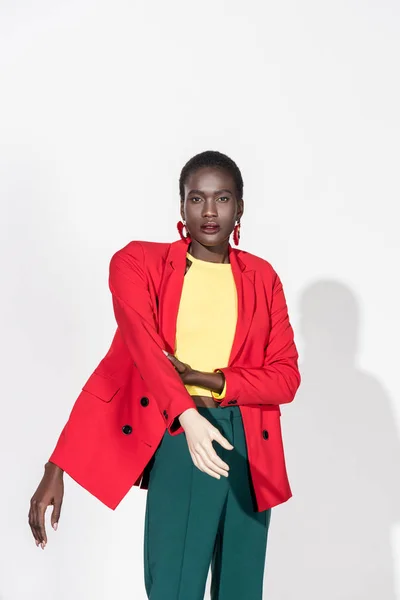 Young stylish african american woman with hand on dummy looking at camera on white — Stock Photo